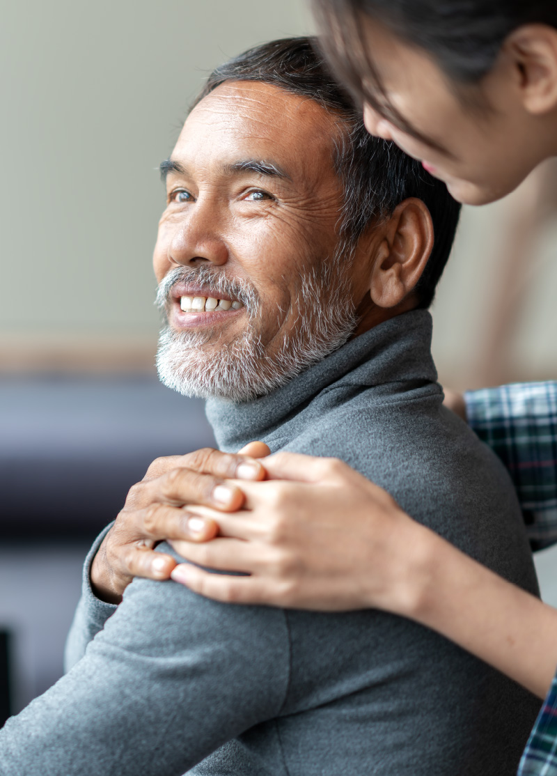 Photo of man being comforted by someone standing behind him.